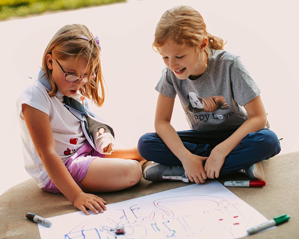 2 girls with ozobots on outside sidewalk