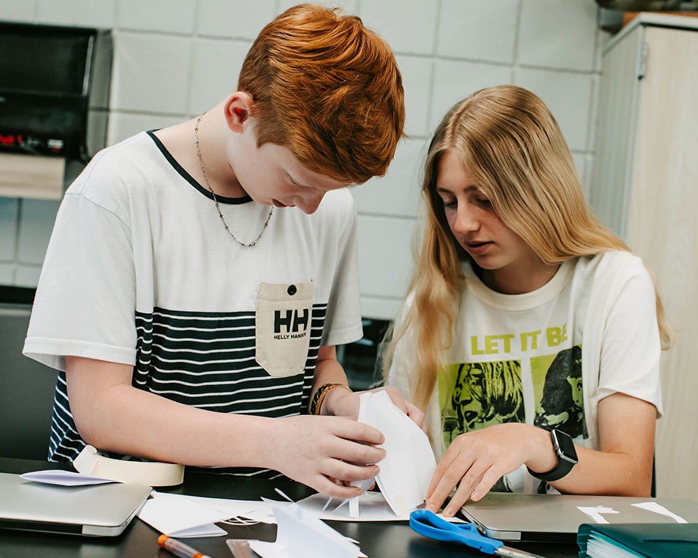 A middle school boy and girl creating with paper