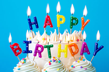 Happy birthday in birthday candles lit on a birthday cake