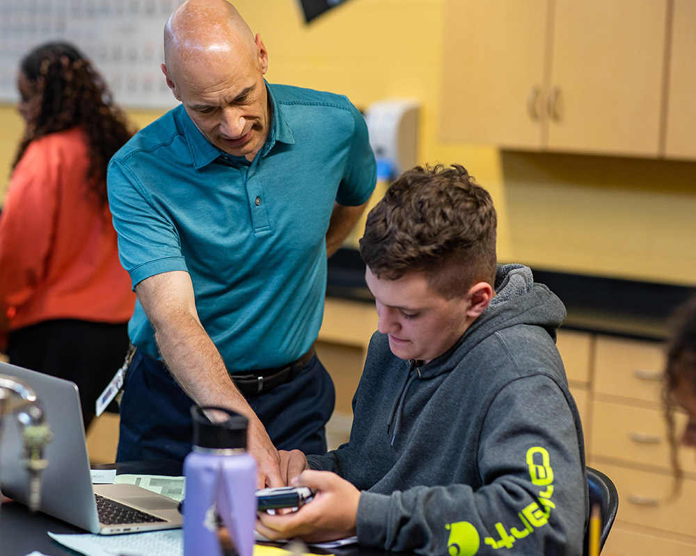 Mr. Eisenga helping a male student with chemistry