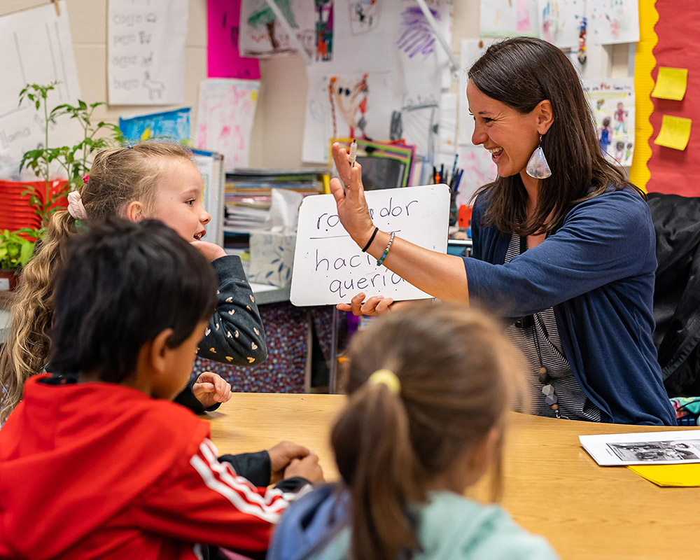 Maestra Klipp Lopez high-fiving a Spanish Immersion kindergarten while learning Spanish words