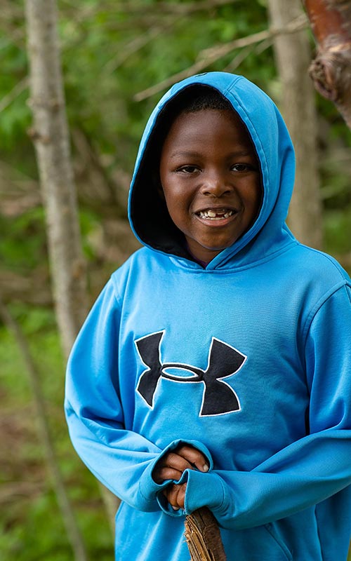 2 Forest School male students working outside on clipboards and smiling at the camera