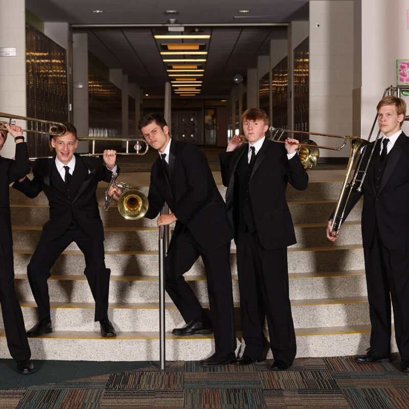 7 high school male trombone players posing with their trombones on the HCHS steps.