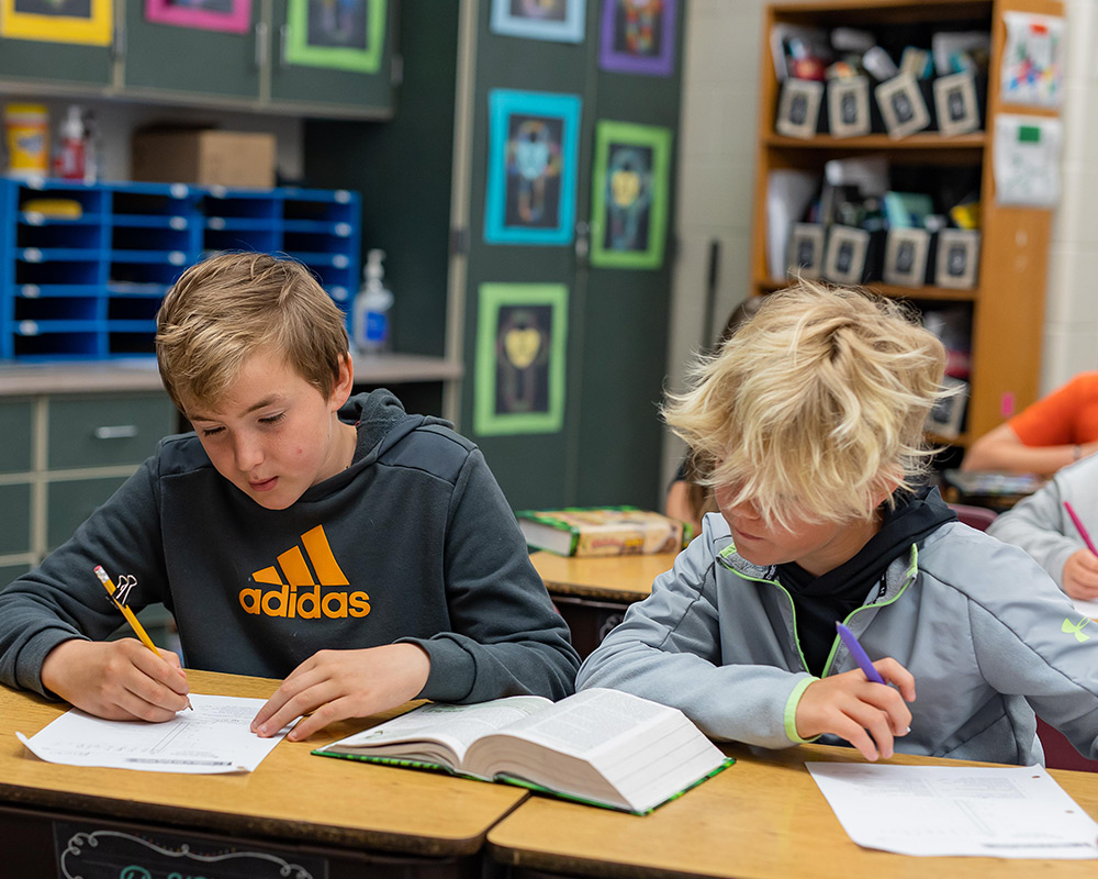 2 boys reading the Bible and answering questions on a worksheet together