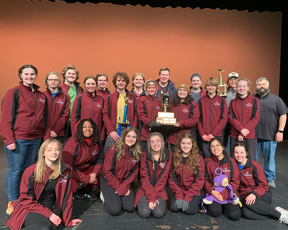 MIFA team holding up their trophies, all dressed in their maroon jackets.