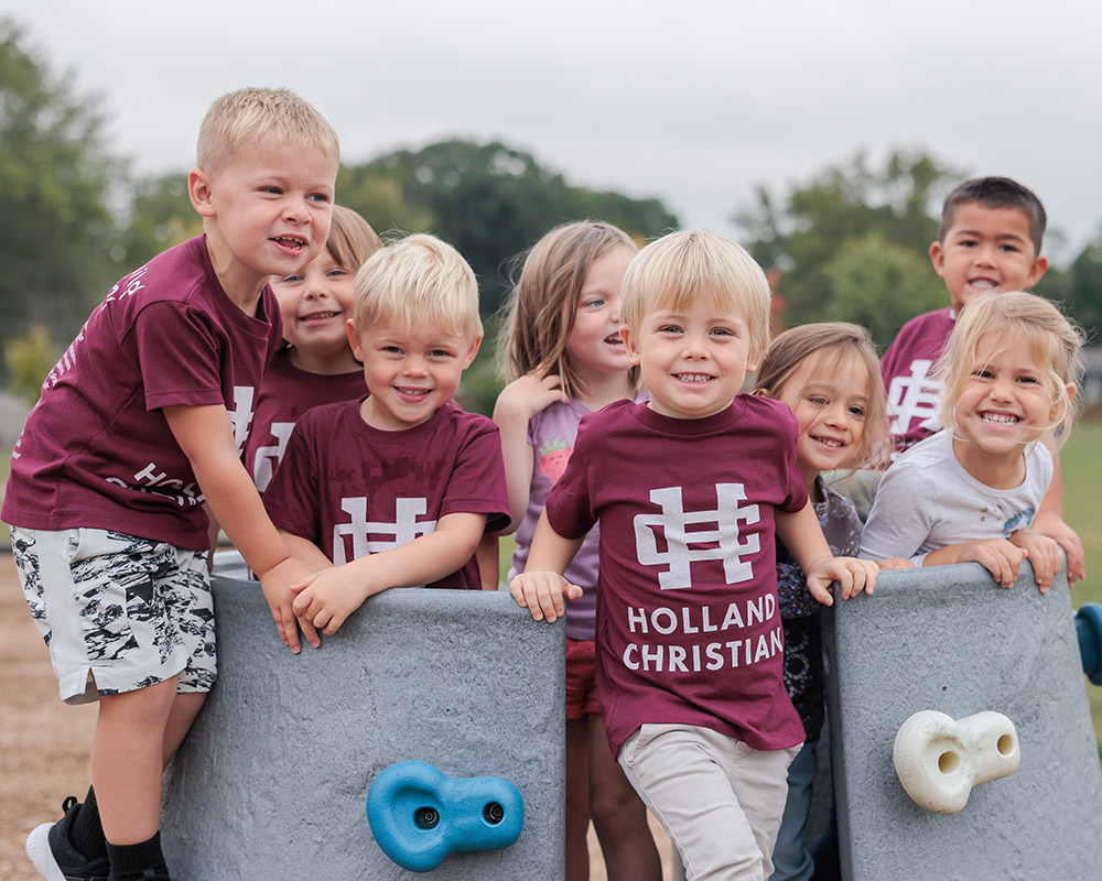 Preschool kids on the playground climbing toy smiling at the camera
