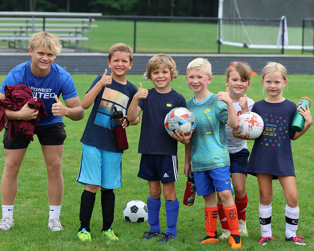 Summer camp little kids soccer team smiling and giving thumbs up