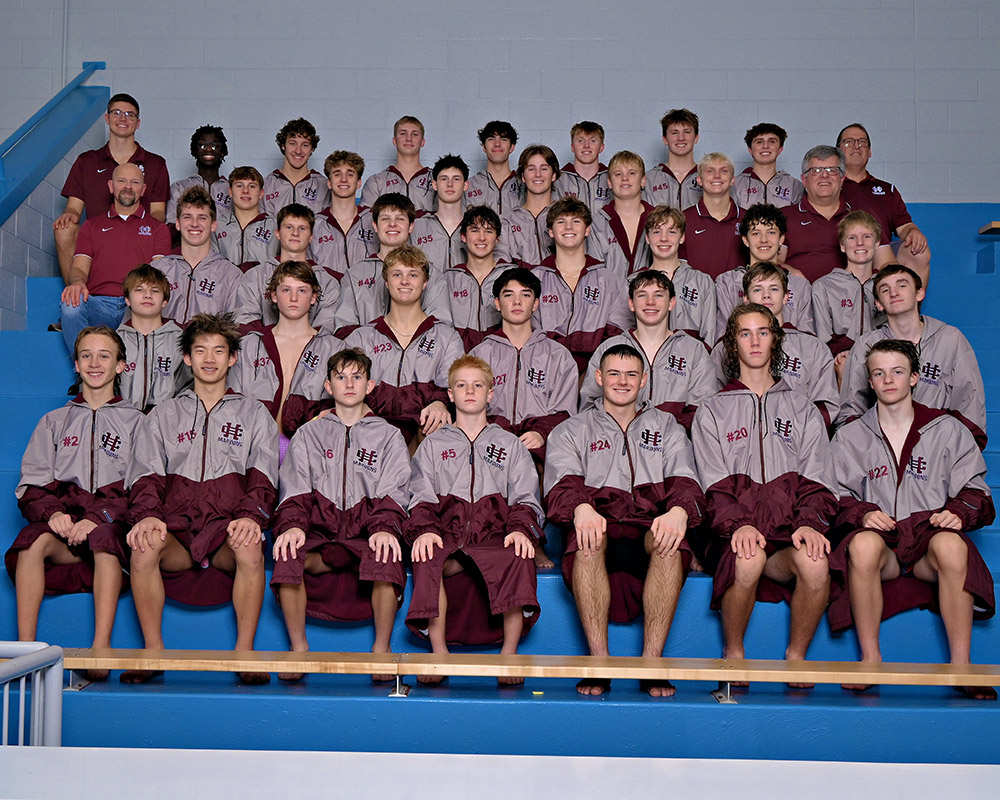 Boys swim team wearing their jackets, smiling at the camera