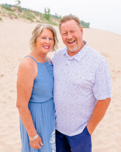 Ken and Judi Draisma posing on the beach, smiling at the camera.