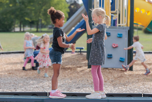 Two elementary girls playing clapping games on the playground.
