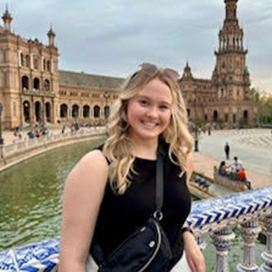 Taylor Byrne smiling at the camera on a bridge in Europe.