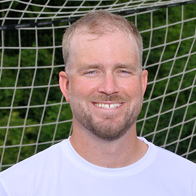 Eric Rietveld smiling at the camera in front of the soccer goal.