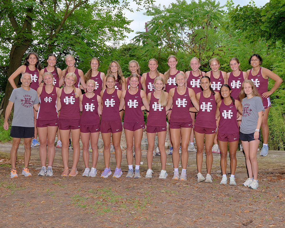 Girls cross country team standing outside in uniform smiling at the camera