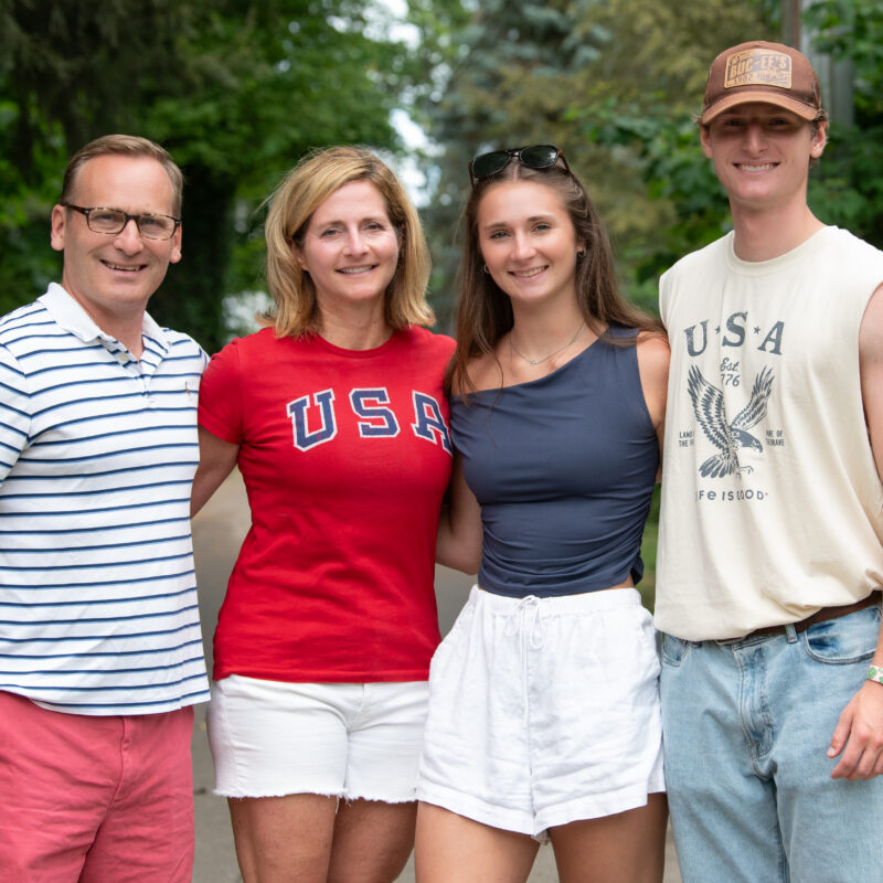 Four members of the Armstrong family smiling at the camera, standing outside