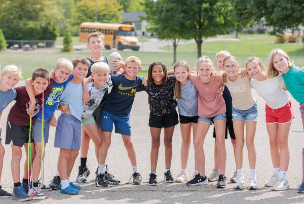 パインリッジの生徒たちは、校庭でショートパンツ姿で並んでカメラに向かって微笑んでいる。