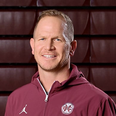 Boys varsity basketball coach smiling at the camera.