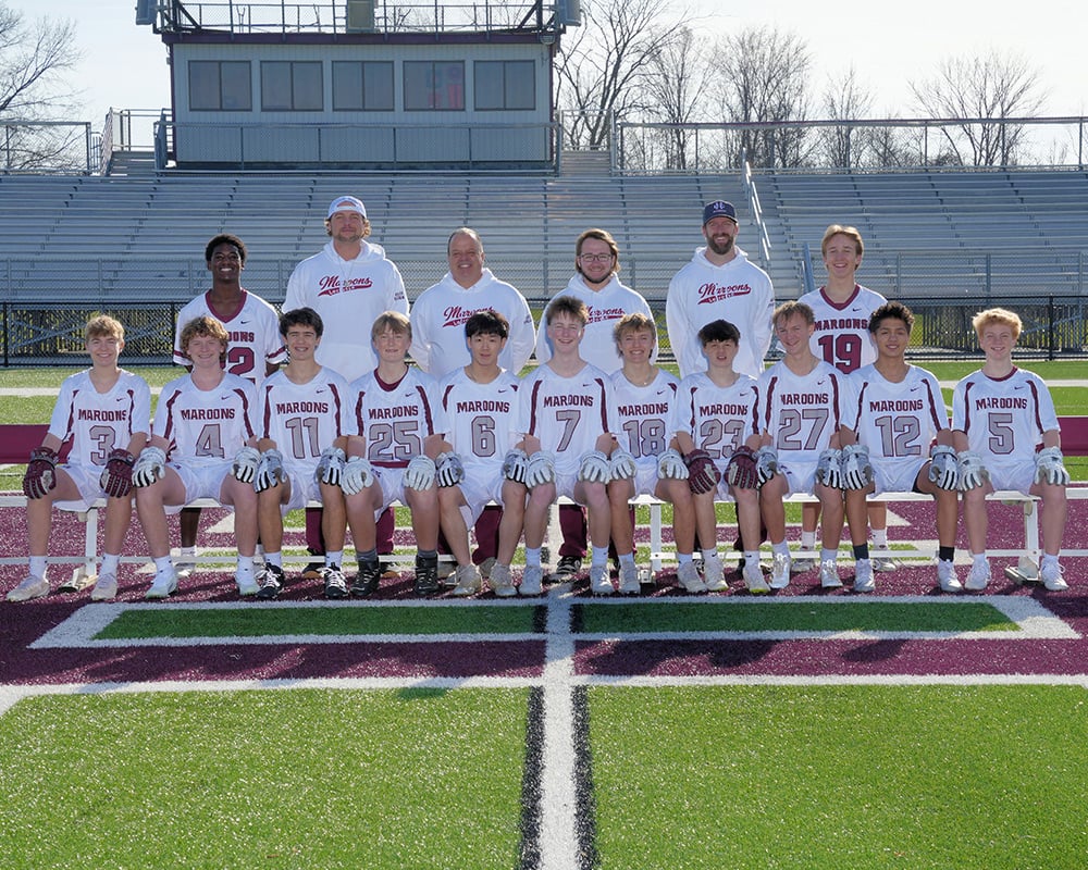 Boys JV lacrosse team lined up and smiling at the camera.