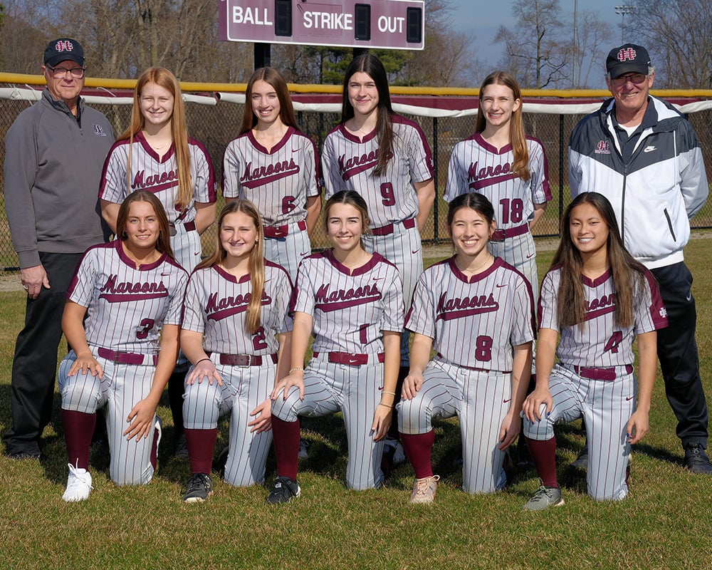 JV girls softball team wearing striped uniforms, outside, smiling at the camera