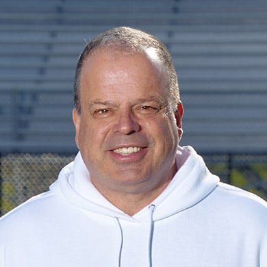 Varsity boys lacrosse coach smiling at the camera