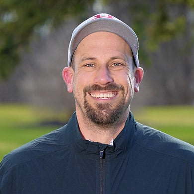 Boys varsity golf coach standing outside, smiling at the camera