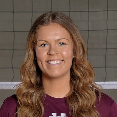 Boys female volleyball coach smiling at the camera.