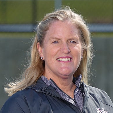 Girls varsity tennis coach smiling at the camera