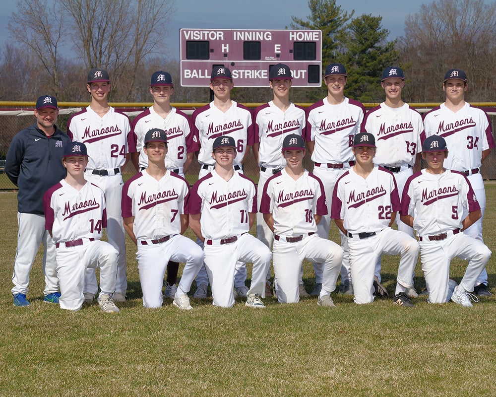Varsity baseball team smiling at the camera, posing outside