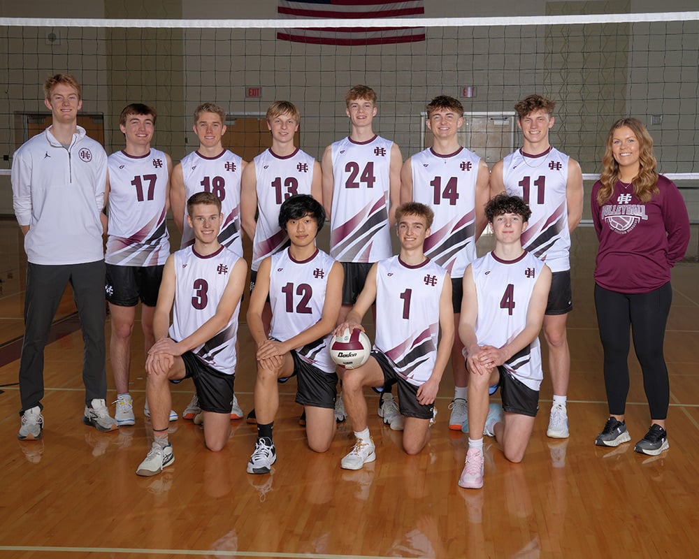 Boys volleyball team and coaches smiling at the camera